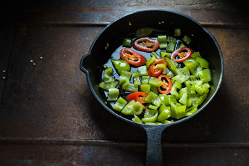 Green pepper and chili on a cast-iron frying pan side view