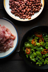 Pieces of chicken, beans. Pepper and chili in a frying pan closeup