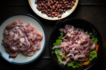 Frying pan with peppers and chicken pieces close-up.