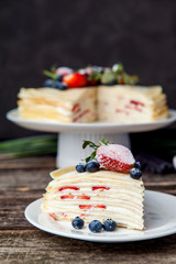 Crepe cake bakery piece with strawberry and vanilla sauce on wood table. Maslenitsa, traditional Russian holiday