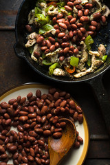 Beans are spread in a frying pan with pepper and chicken top view