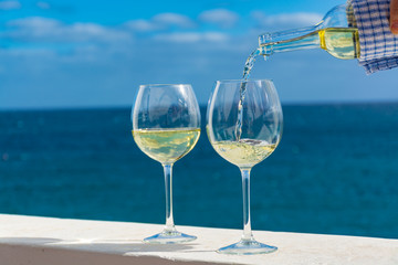 Waiter pouring glass of white wine on outdoor terrace with sea view