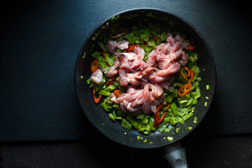 Frying pan with peppers and chicken pieces.