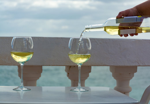 Waiter pouring glass of white wine on outdoor terrace with sea view