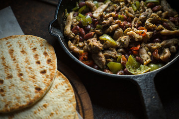 Tortilla on parchment and frying pan with filling side view