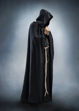 Silhouette of a praying monk, folded hands in prayer. Photo of monk at prayer. Full height. Concept for faith, spirituality and religion