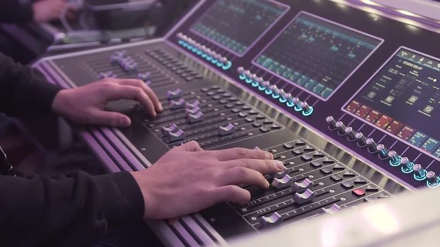 Close- up. Hand of the sound producer. Professional audio operator working on audio mixer knobs. Controls of video and audio mixing console, close up of hands using it