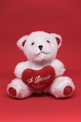 Weißer Teddybär mit roten Ich liebe Dich Herz auf roten Hintergrund