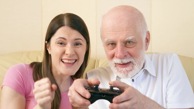 Father and daughter gamers playing video games at home. Addicted senior and teen players with remote controller of game console. Cybersport for active modern elderly people