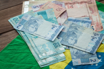 Brazilian money / reais and flag on the wooden table.
