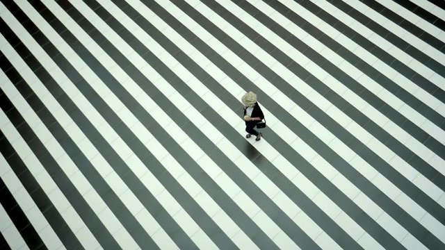 a young woman with blond hair walking along a striped road, a single lady crossing a pavement or art space with a cup of coffee in her hands, she speaks on the smartphone