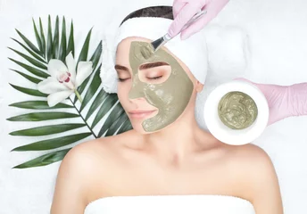 Foto op Plexiglas The procedure for applying a mask from clay to the face of a beautiful woman. Spa treatments and care of the face in the beauty salon. © Dimid