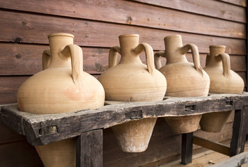 ancient handmade clay jugs for beverage storage on a wooden support 