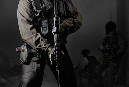 Closeup black and white photo of equipped military soldiers holding a gun and attacking.