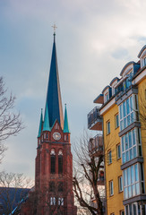Fototapeta na wymiar old church tower next to an apartment house