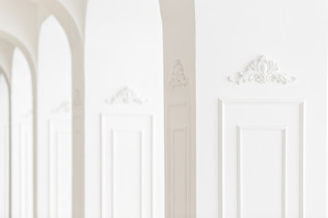 focus in the foreground. Expensive luxury interior. Stucco elements on line of light columns. White patterned. Mouldings element from gypsum. Roccoco style