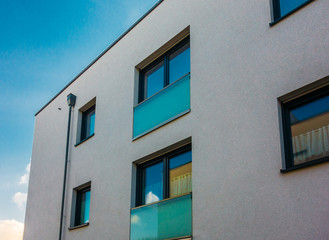 Fototapeta na wymiar white big apartment facade with green glass windows