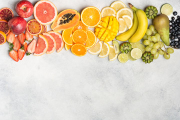 Raibow fruits and berries, strawberries, mango, grapes, bananas, grapefruit on the off white table, copy space for text, top view, selective focus