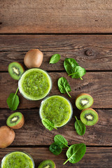 Fototapeta na wymiar Kiwi smoothie drink of spinach leaves and fresh fruits on wooden rustic table, healthy detox diet