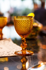 Yellow water glass with engraving stands on the table.