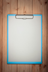 clipboard with blank white paper sheet on wood table top view with copy space.