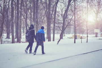 Fototapeta na wymiar boys walking on snow covered park