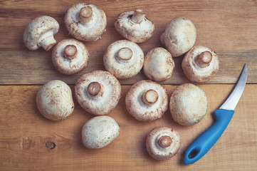 white champignons and knife on wooden table