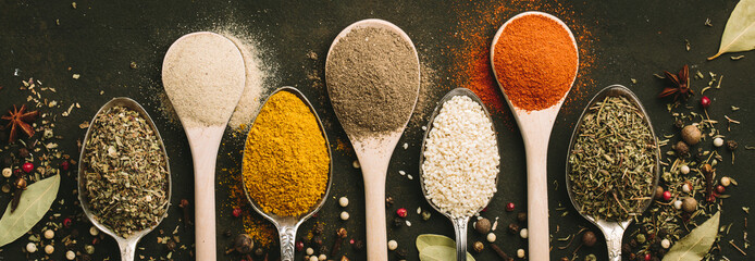 Spices and herbs over black stone background. Top view. Copy space