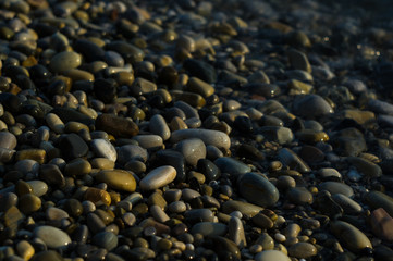 pebble stones on the sea beach, the rolling waves of the sea with foam