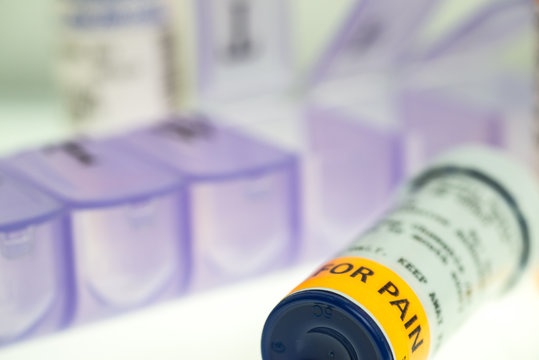horizontal image of prescription pain medication bottles and weekly pill organizer. shallow depth of field with room for copy. 