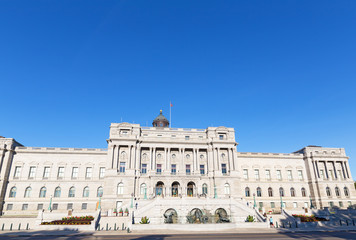 Fototapeta premium Grand historic architecture of The Library of Congress, Thomas Jefferson Building in Washington DC, USA. Joggers take a break on the library steps under clear blue skies on a hot summer morning.