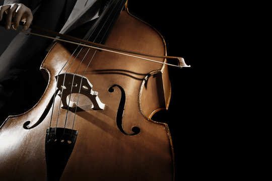 Double bass player. Hands playing contrabass strings with bow