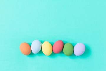 pastel easter eggs on green background in top view