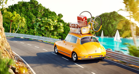 Cute little retro car with suitcases and bicycle on top goes by the road along beautiful harbor between mountain in summer day.