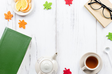 Book, cup of tea, teapot, candy and glasses, flat lay. Cozy background, reading concept. Copy space