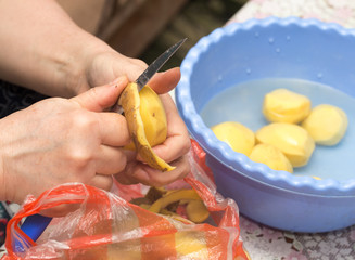A woman peeling potatoes with a knife