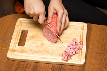 Slicing sausage with a knife on the board