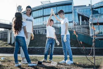 Perfect team. Joyful nice positive people standing together and giving each other a high five while working in team