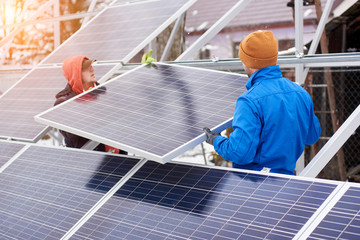 Engineers installing solar panels in winter. Outdoors. Workers are dressed in uniform and warmed with additional clothes