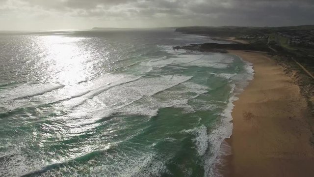 Static aerial shot of beautiful ocean coastline with waves crushing on sandy beach in Australia at sunset