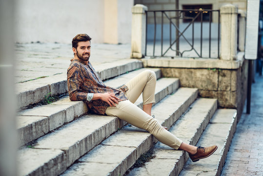 Young bearded man, model of fashion, wearing shirt in urban background.