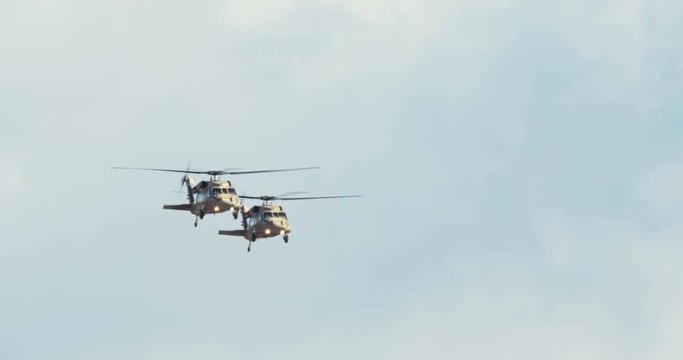 Two blackhawk helicopters fly at low altitude