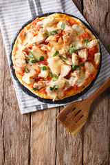 Buffalo pizza with chicken breast, tomato concasse and cheese close-up. vertical top view