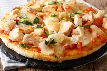 Spicy pizza with chicken, tomatoes, buffalo sauce and cheese close-up on the table. horizontal