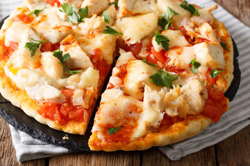 American sliced pizza with chicken, tomatoes, buffalo sauce and cheese close-up on the table. horizontal