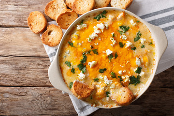 American food: hot chicken buffalo dip close-up in a baking dish with toasted bread. Horizontal top view