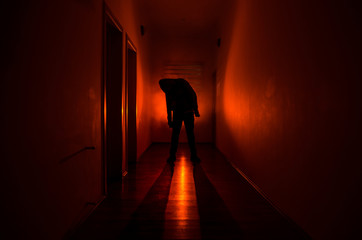 Dark corridor with cabinet doors and lights with silhouette of spooky horror man standing with...