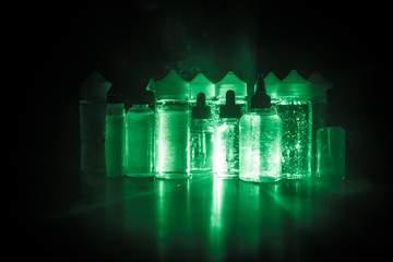 Vape concept. Smoke clouds and vape liquid bottles on dark background. Light effects