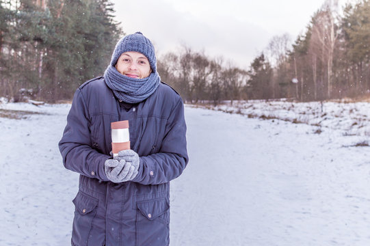young man holds thermos in the woods in winter. concept