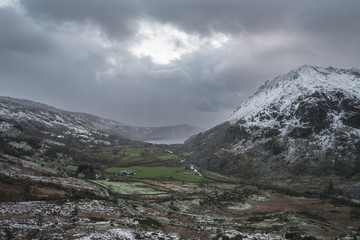 Beautiful Winter landscape image in Llyn Gwynant in Snowdonia National Park with snow capped mountains in background
